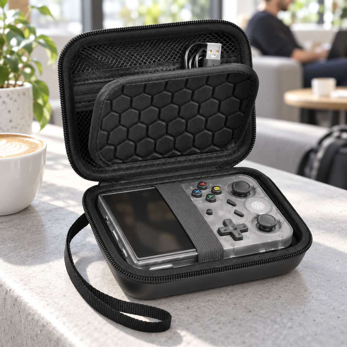 Black ALKOO retro handheld case with screen divider, console and charging cable on a cafe bench
