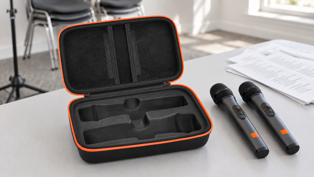 Open black ALKOO microphone case with orange zipper, two microphone recesses and two mesh lid pockets on a community music-room table.