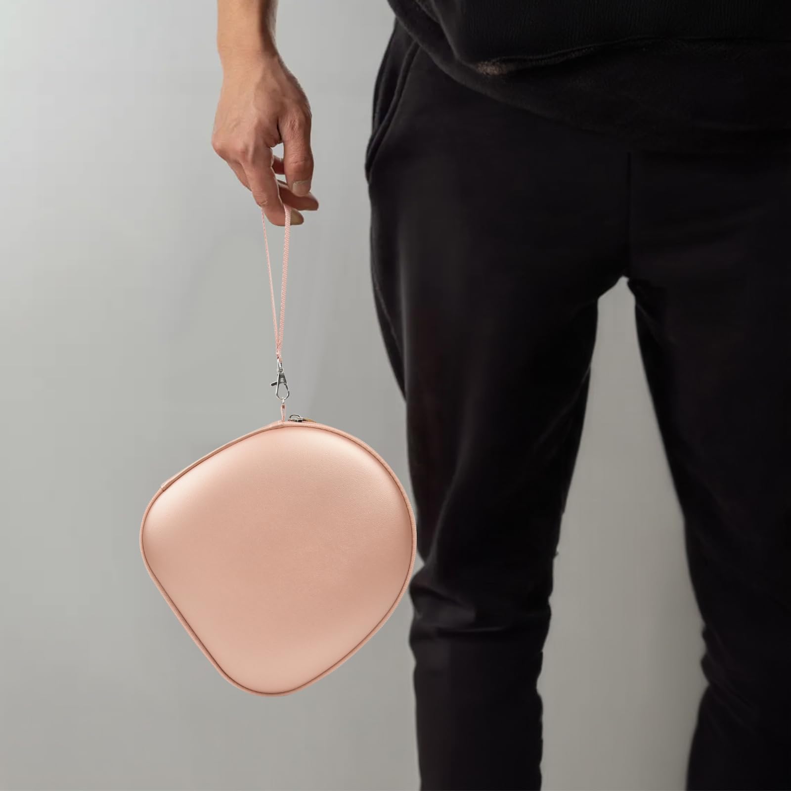 Person carrying the rose gold headphone case by its wrist strap
