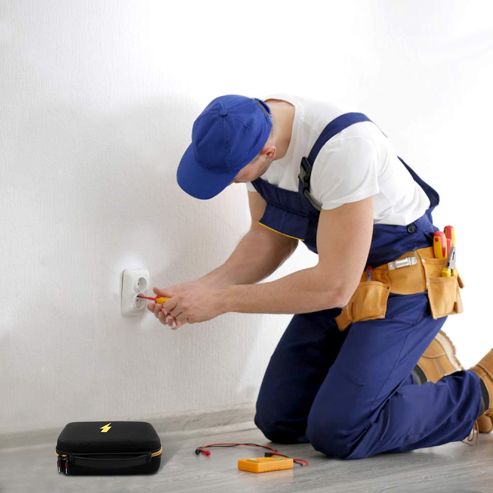 Electrician using test equipment beside the closed black and yellow multimeter case