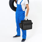 Worker carrying the black portable air compressor bag by its top handle