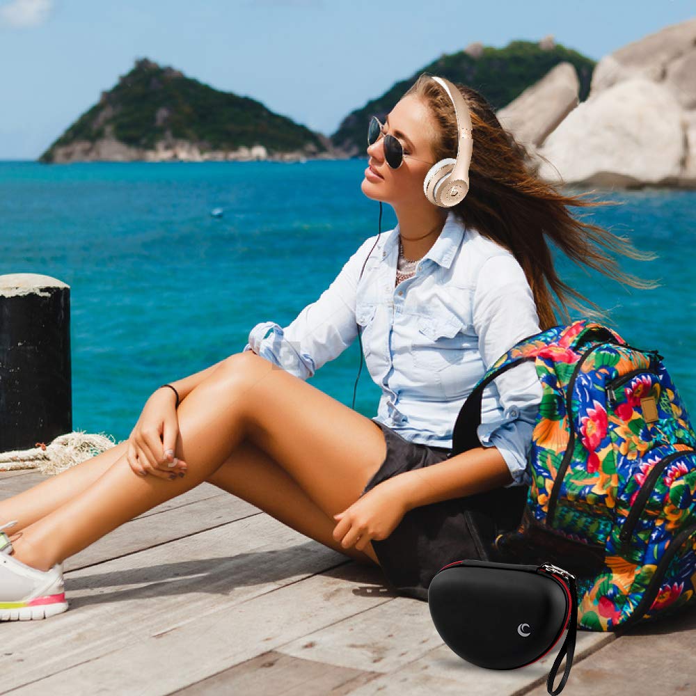 Woman wearing headphones beside the black and red case during outdoor travel
