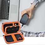 Open black and orange SSD organizer beside a SanDisk drive connected to a laptop
