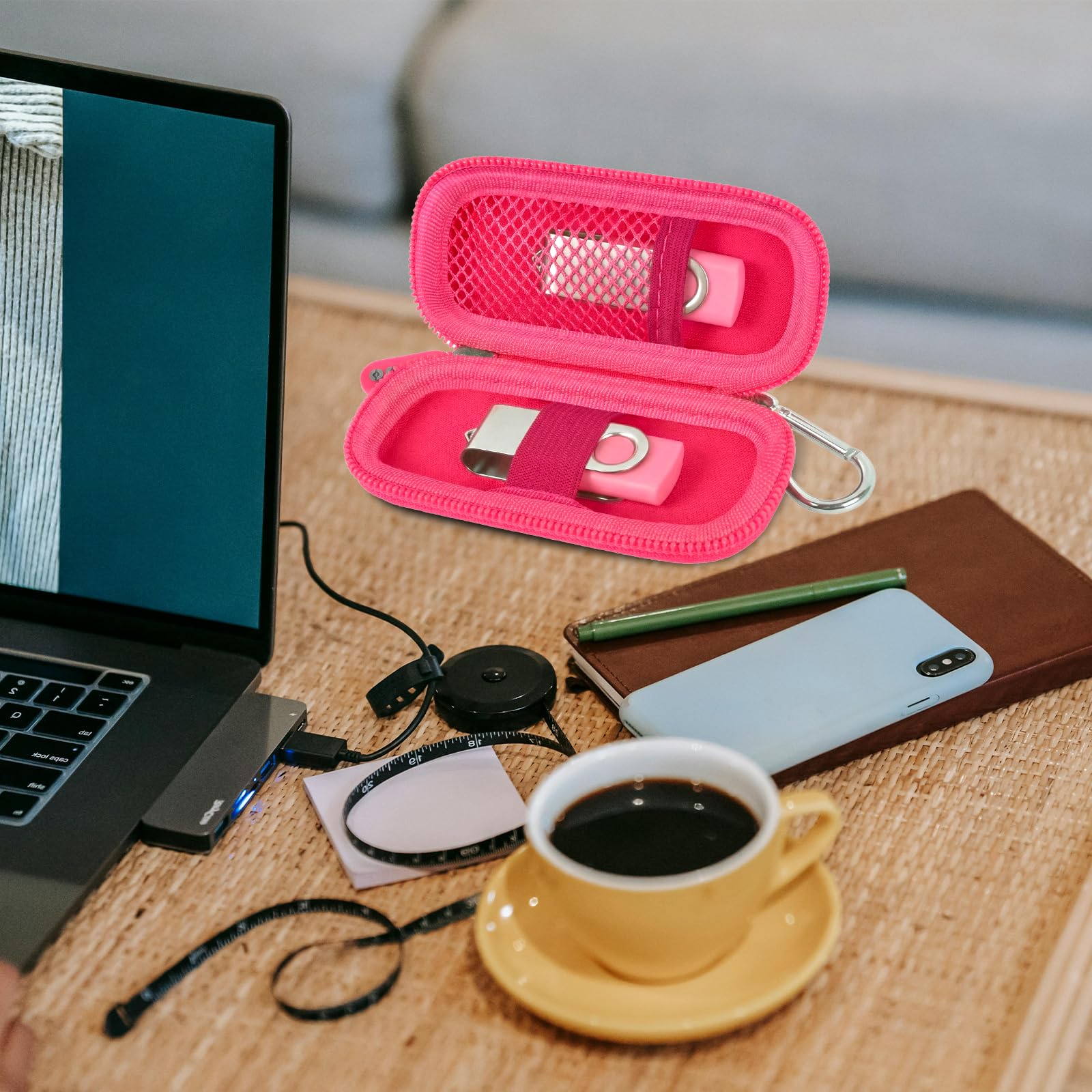 Hot pink USB flash drive and SD card storage case open on a desk with electronics accessories