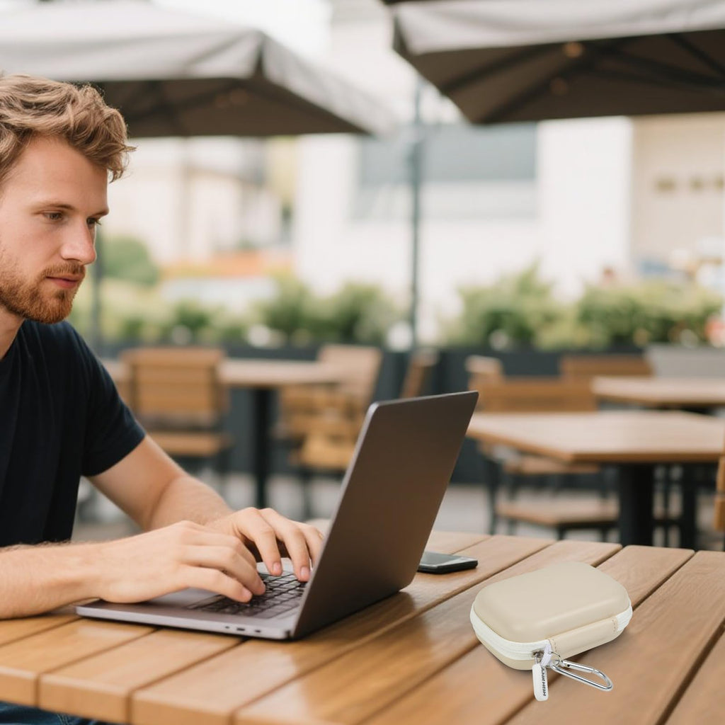 Ivory portable SSD case beside a laptop at an outdoor cafe