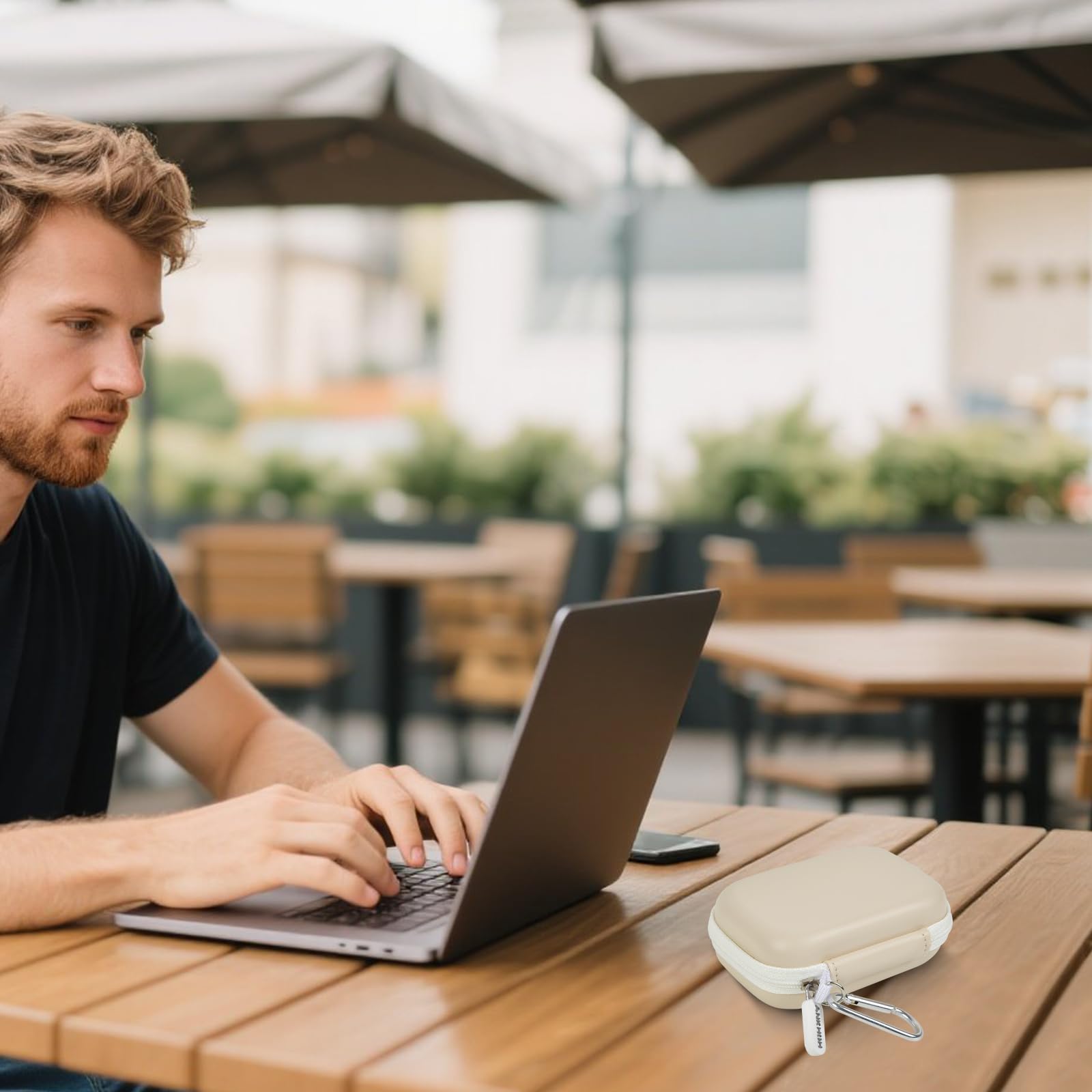 Ivory portable SSD case beside a laptop at an outdoor cafe