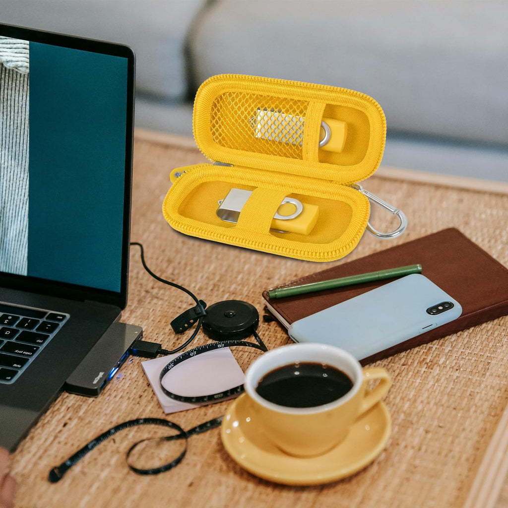Yellow USB flash drive and SD card storage case open on a desk with electronics accessories