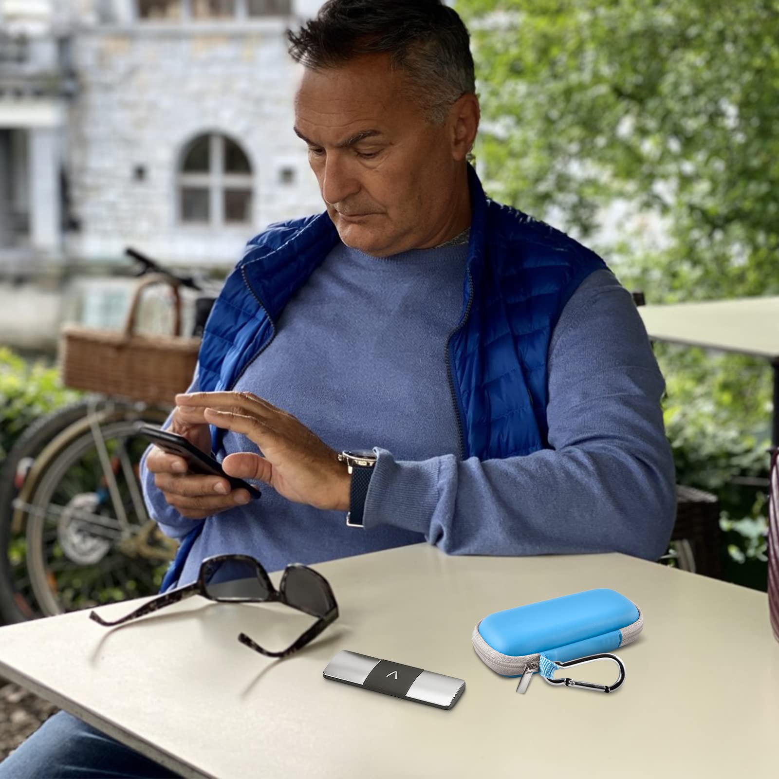 Man using a KardiaMobile device beside the open blue travel case