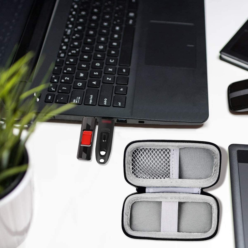 Black USB flash drive and SD card storage case open interior holding drives beside a laptop