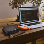 Black hard drive case beside a LaCie Rugged Mini drive connected to a laptop