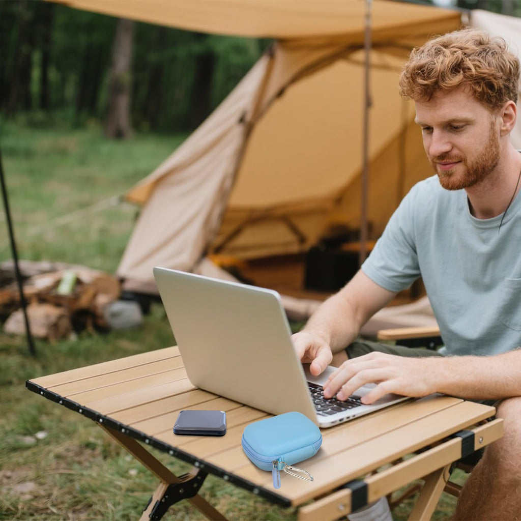 Light blue SSD case beside a portable drive during outdoor laptop use