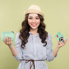 Woman holding the mint green camera case beside a compact digital camera