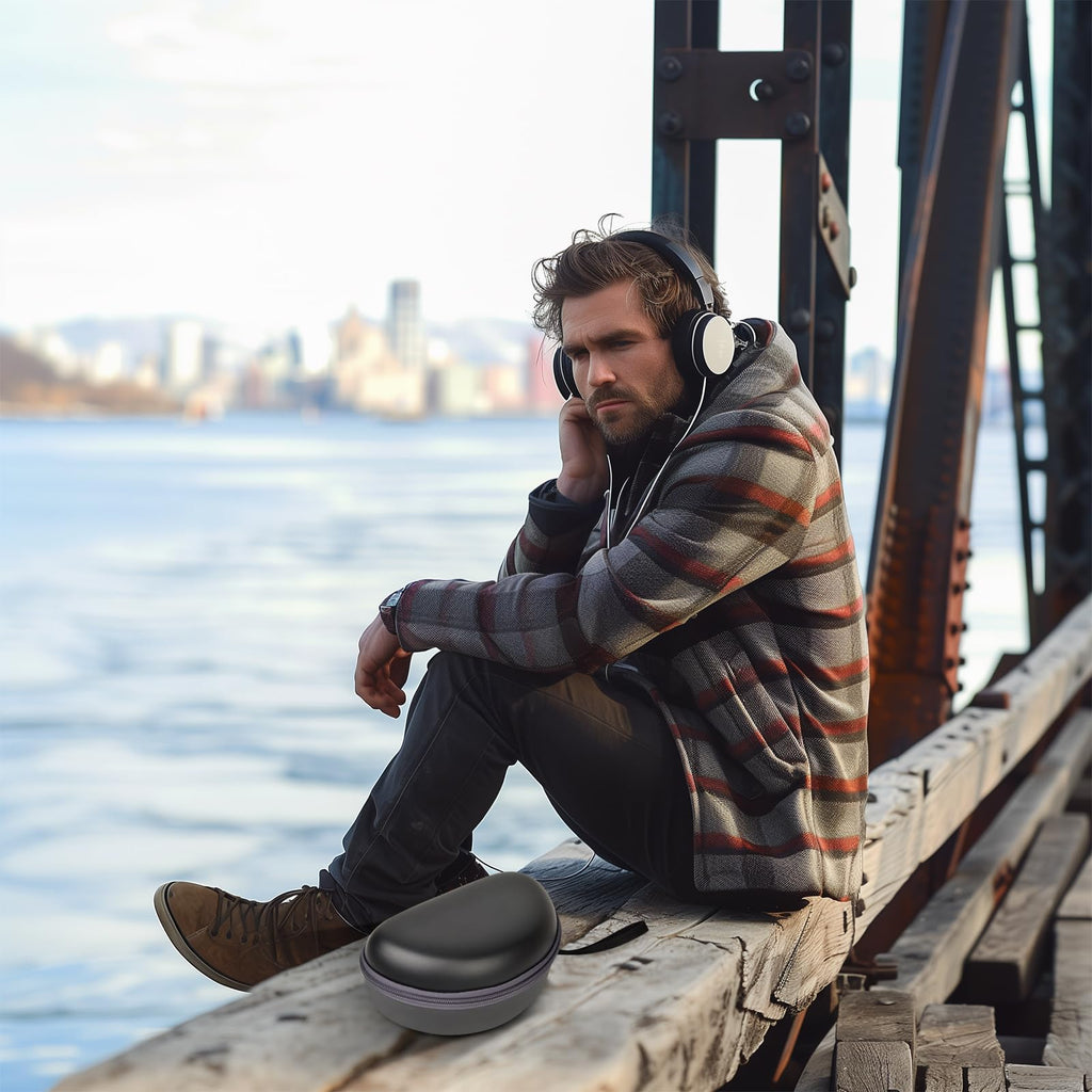 Man wearing headphones beside the open black travel case at a waterfront