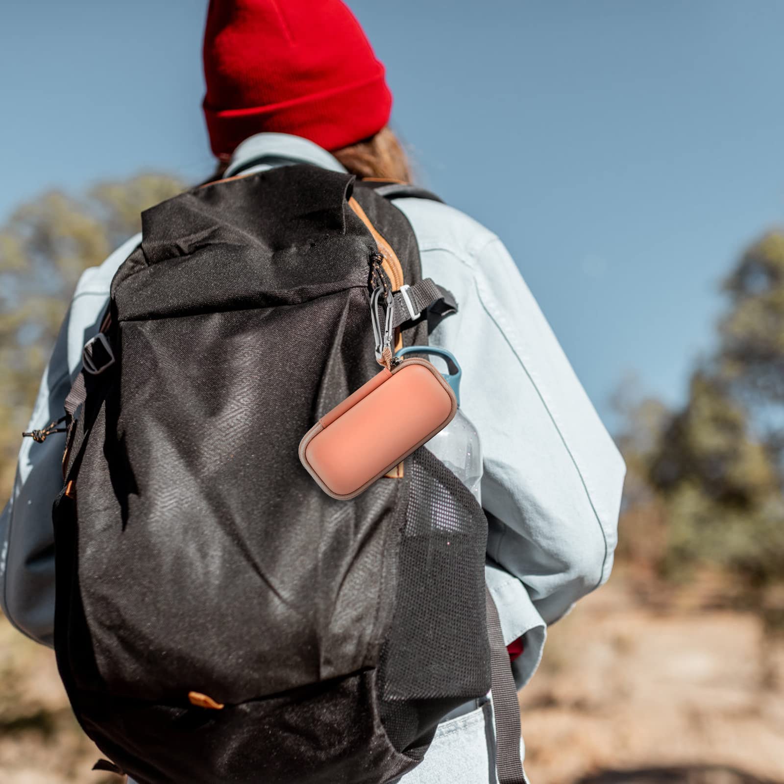 Peach KardiaMobile case clipped to a hiking backpack