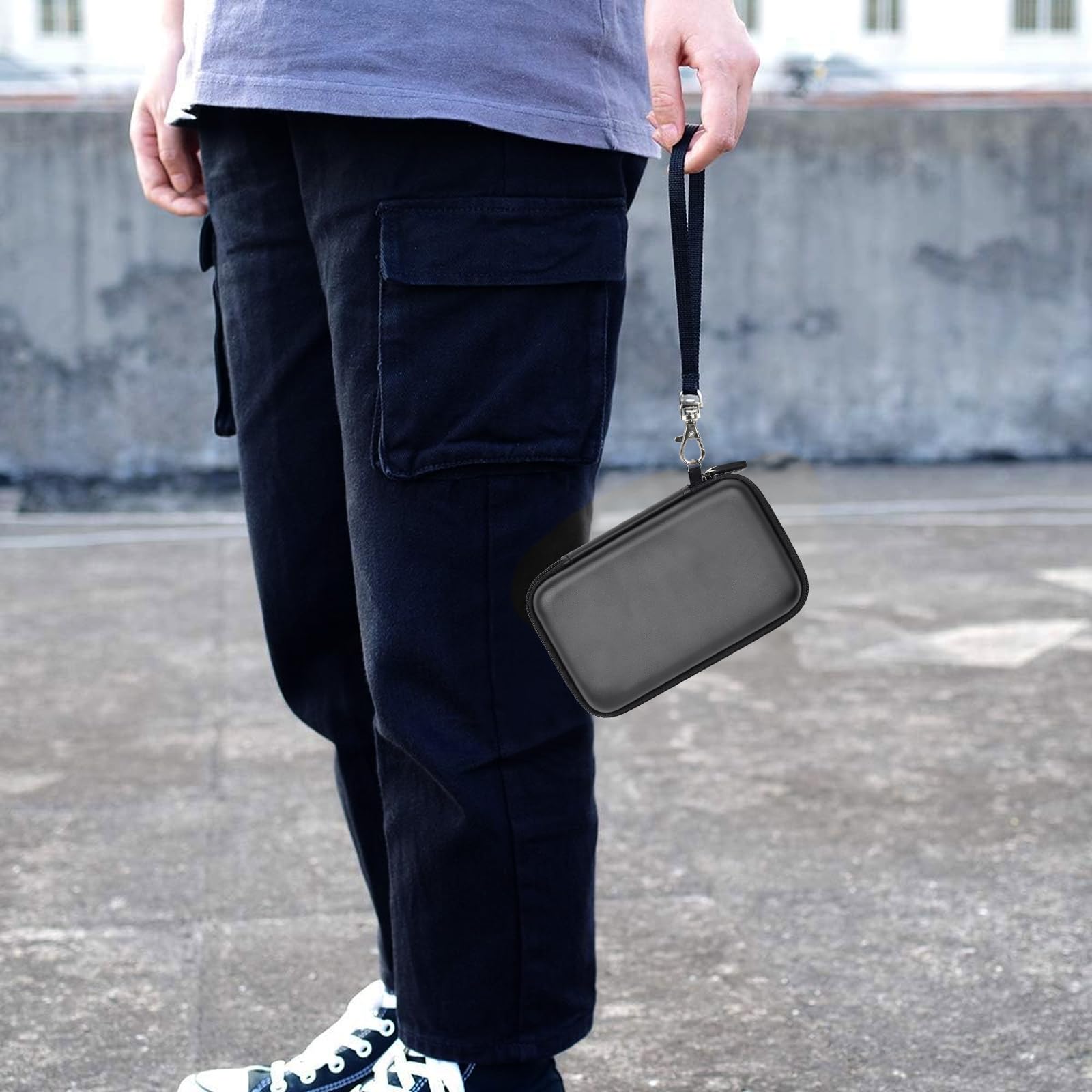 Black retro handheld console carrying case for R36MAX and R36 PRO carried by the wrist strap outdoors