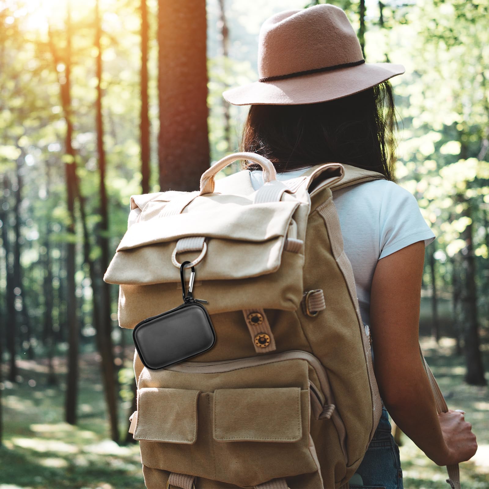 Black portable SSD case clipped to a hiking backpack