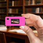 Hot pink silicone case for Kodak Charmera keychain camera shown on the camera while taking a photo indoors