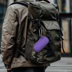 Purple USB flash drive and SD card storage case clipped to a backpack