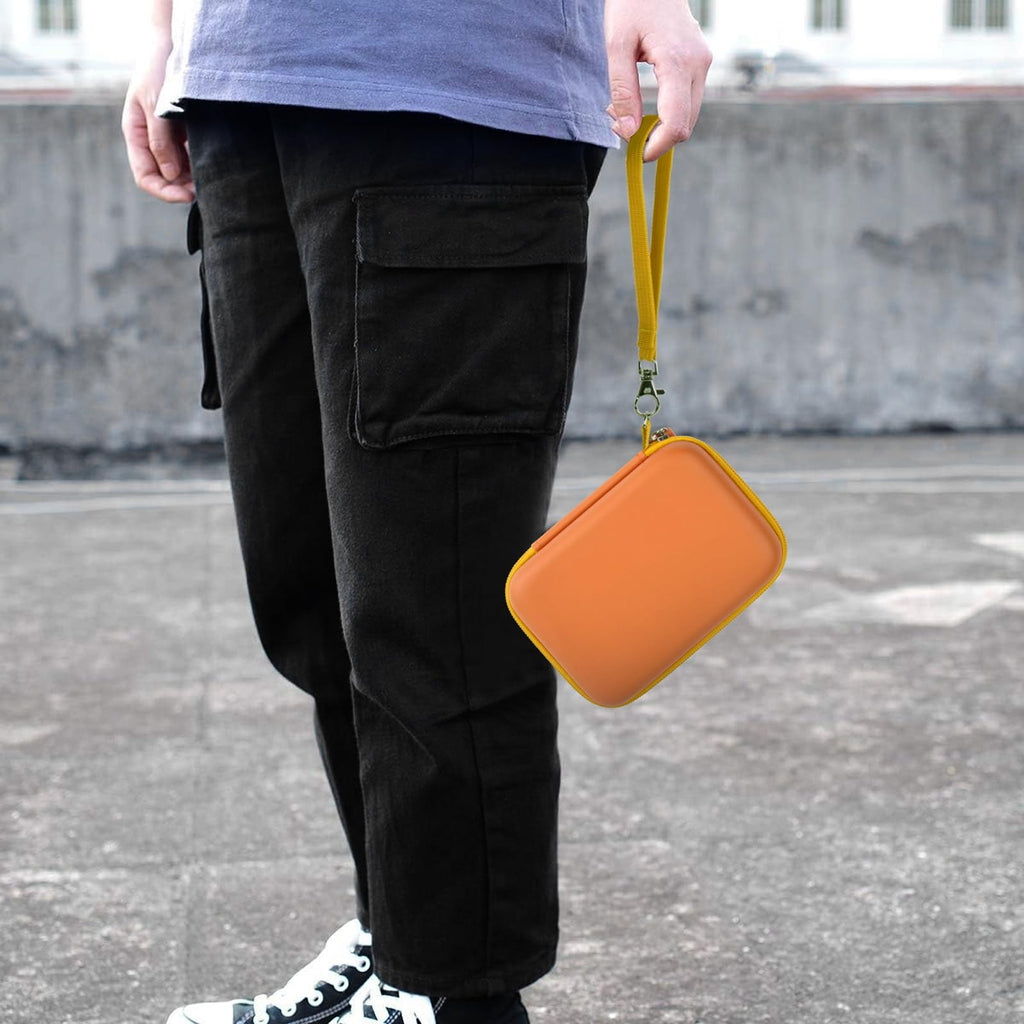 Orange retro handheld console carrying case carried by the wrist strap outdoors