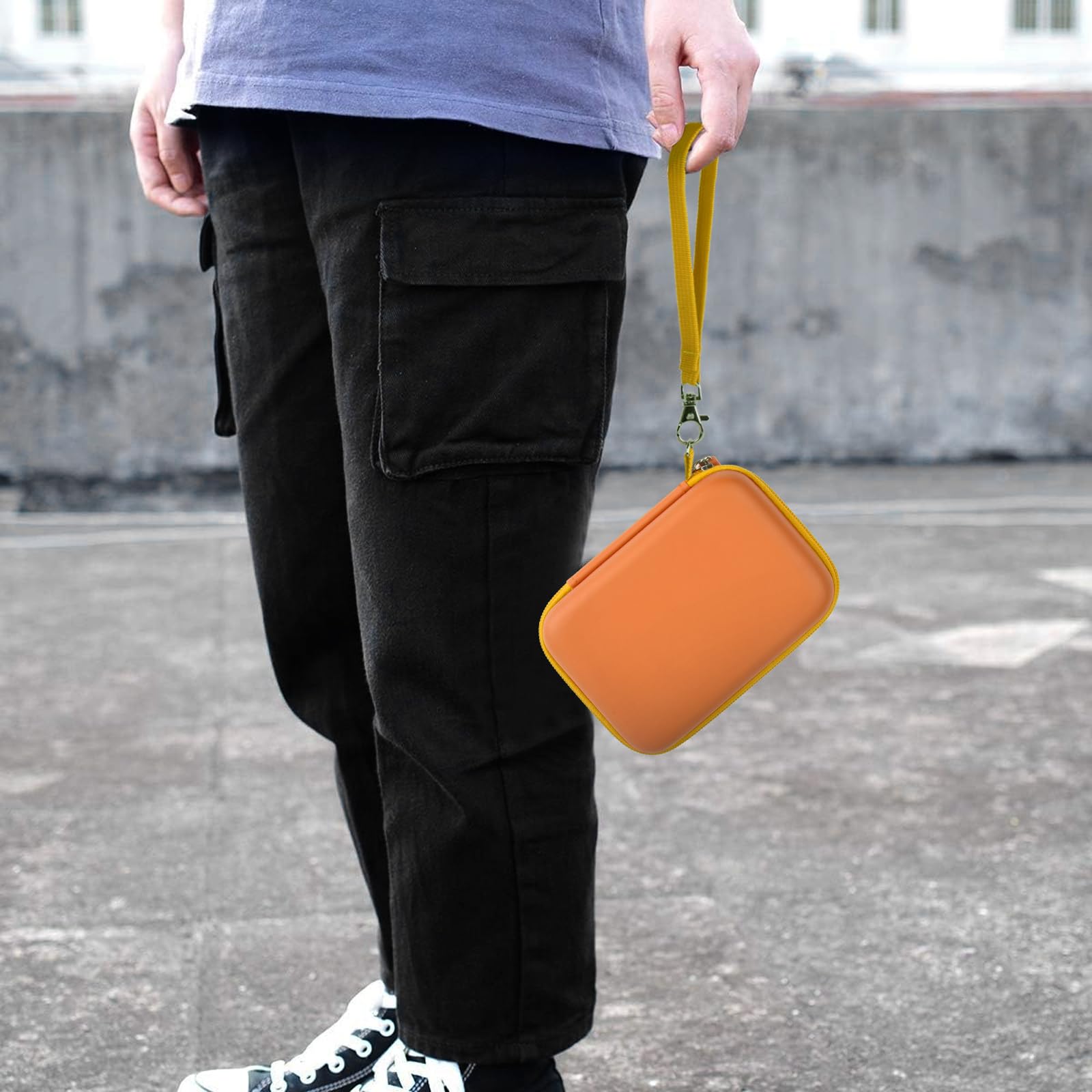 Orange retro handheld console carrying case carried by the wrist strap outdoors