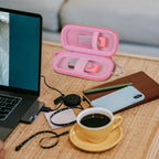 Light pink USB flash drive and SD card storage case open on a desk with electronics accessories