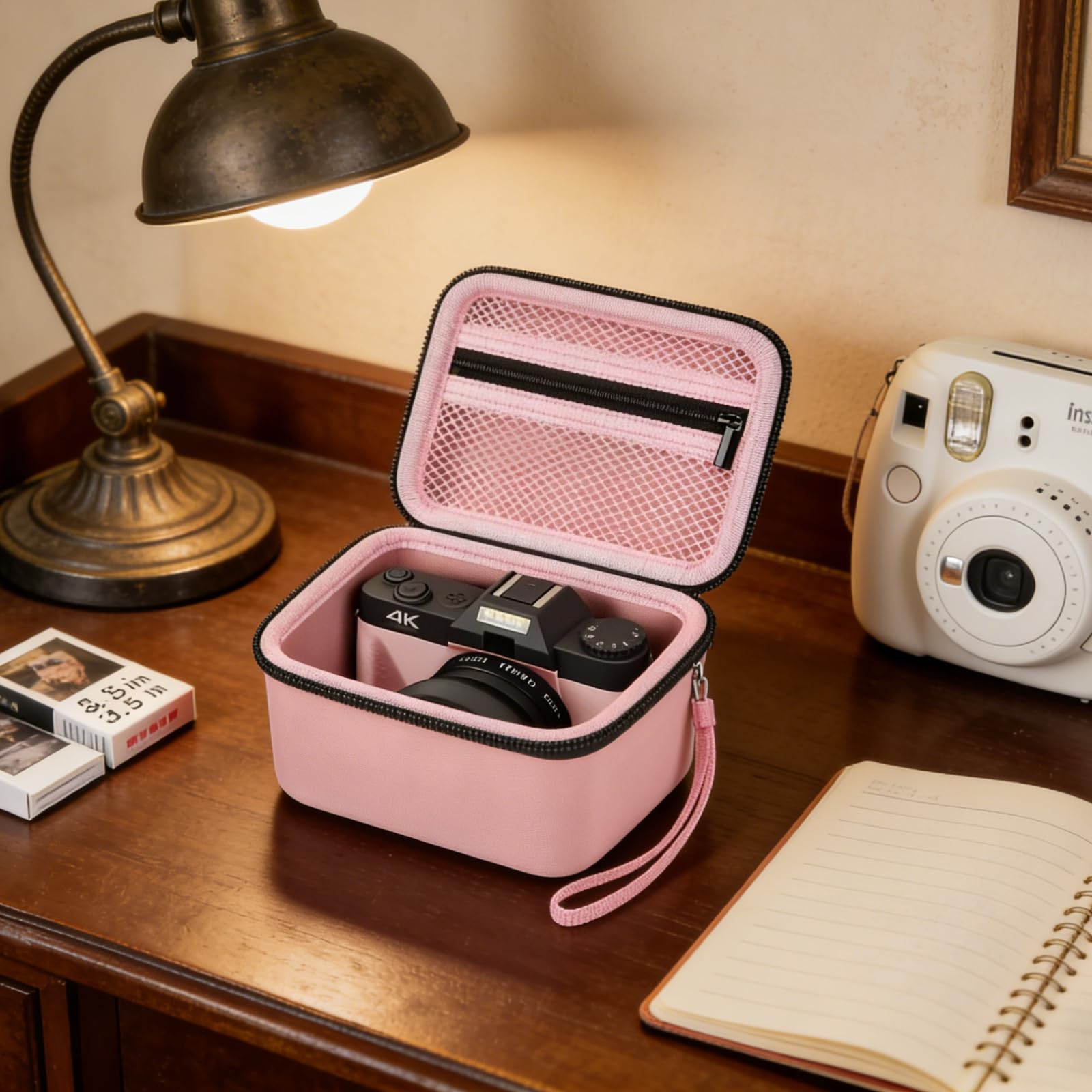 Open pink camera case organizing a camera and accessories on a desk