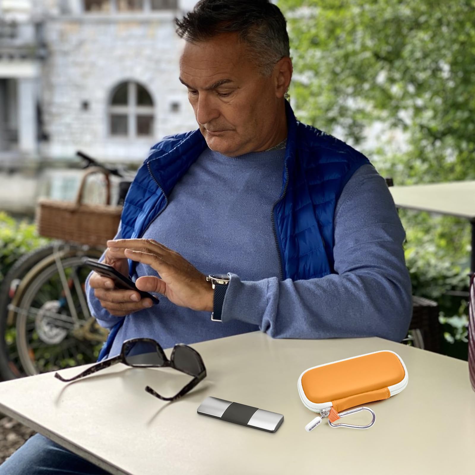 Man using a KardiaMobile device beside the open orange travel case