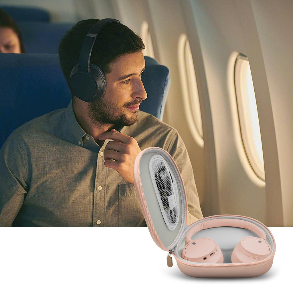 Traveler using headphones beside the open rose gold carrying case on an airplane