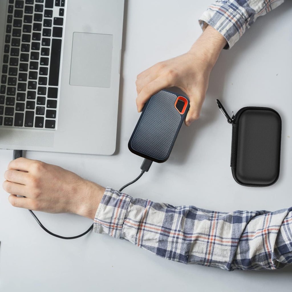 Black SSD organizer beside a SanDisk drive connected to a laptop
