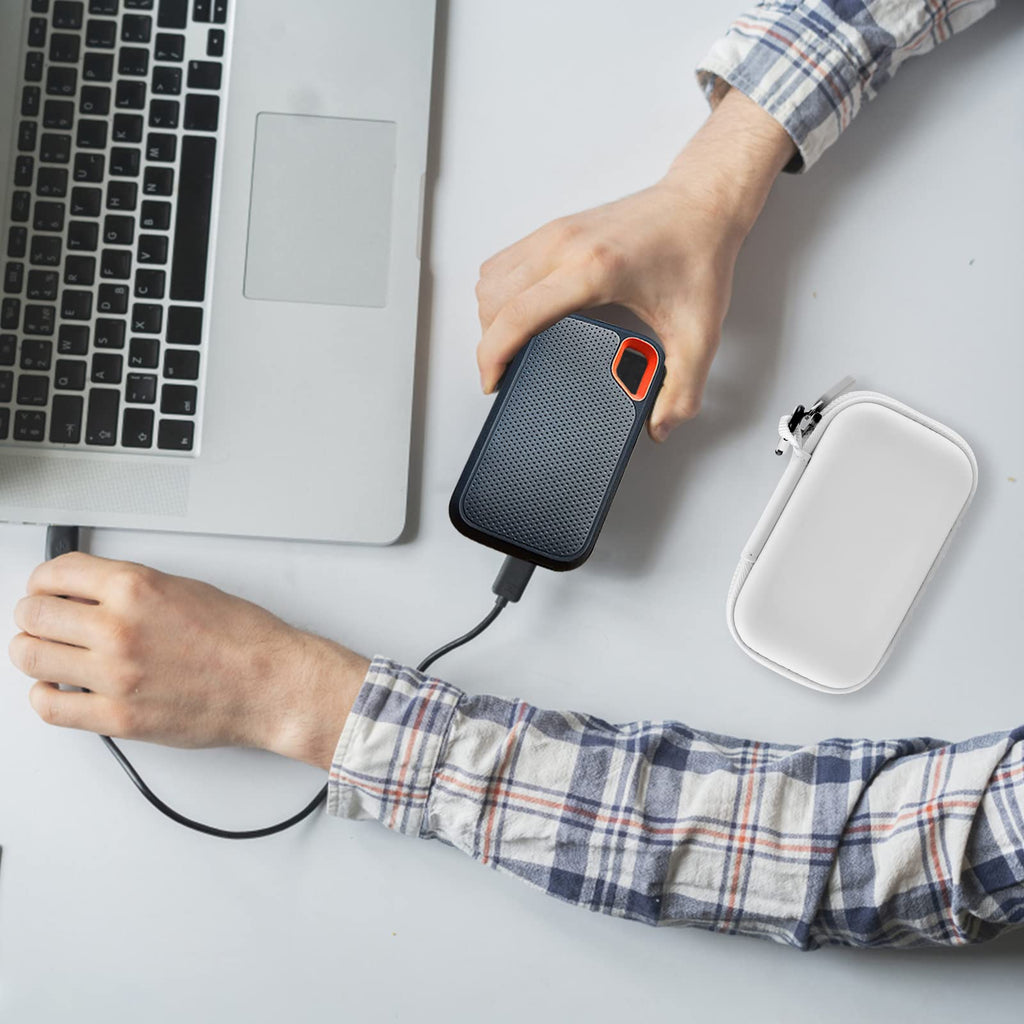 SanDisk portable SSD and white case beside a laptop during use