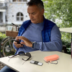 Man using a KardiaMobile device beside the open peach travel case