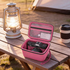 Hot pink camera case beside camping equipment on an outdoor table