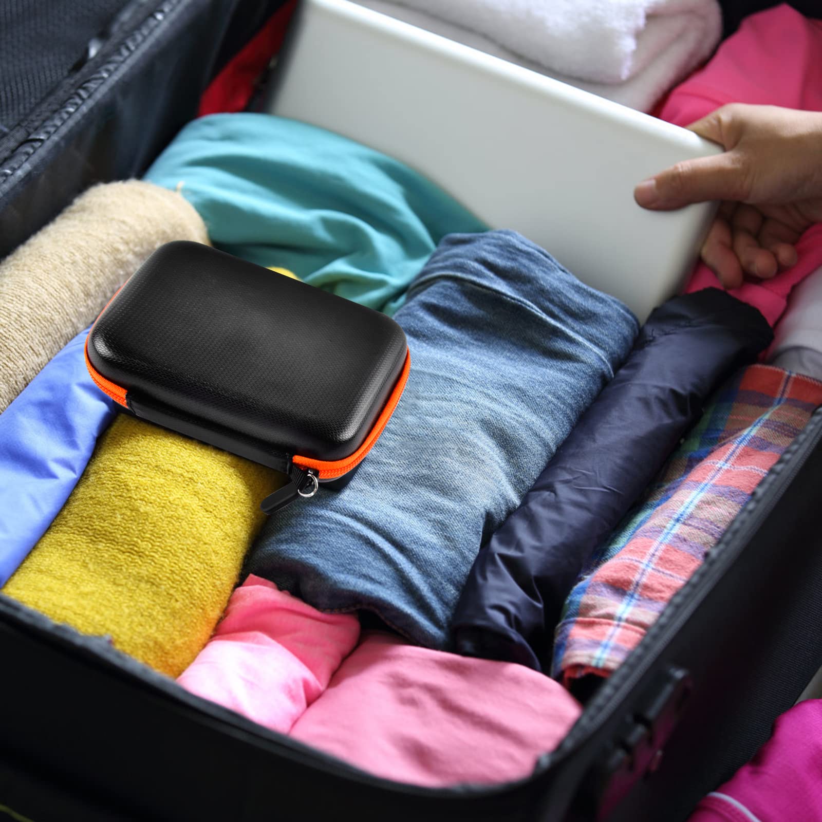 Black and orange hard drive case packed inside a suitcase for travel