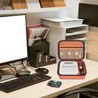 Open orange label maker case organizing a printer and tapes on an office desk