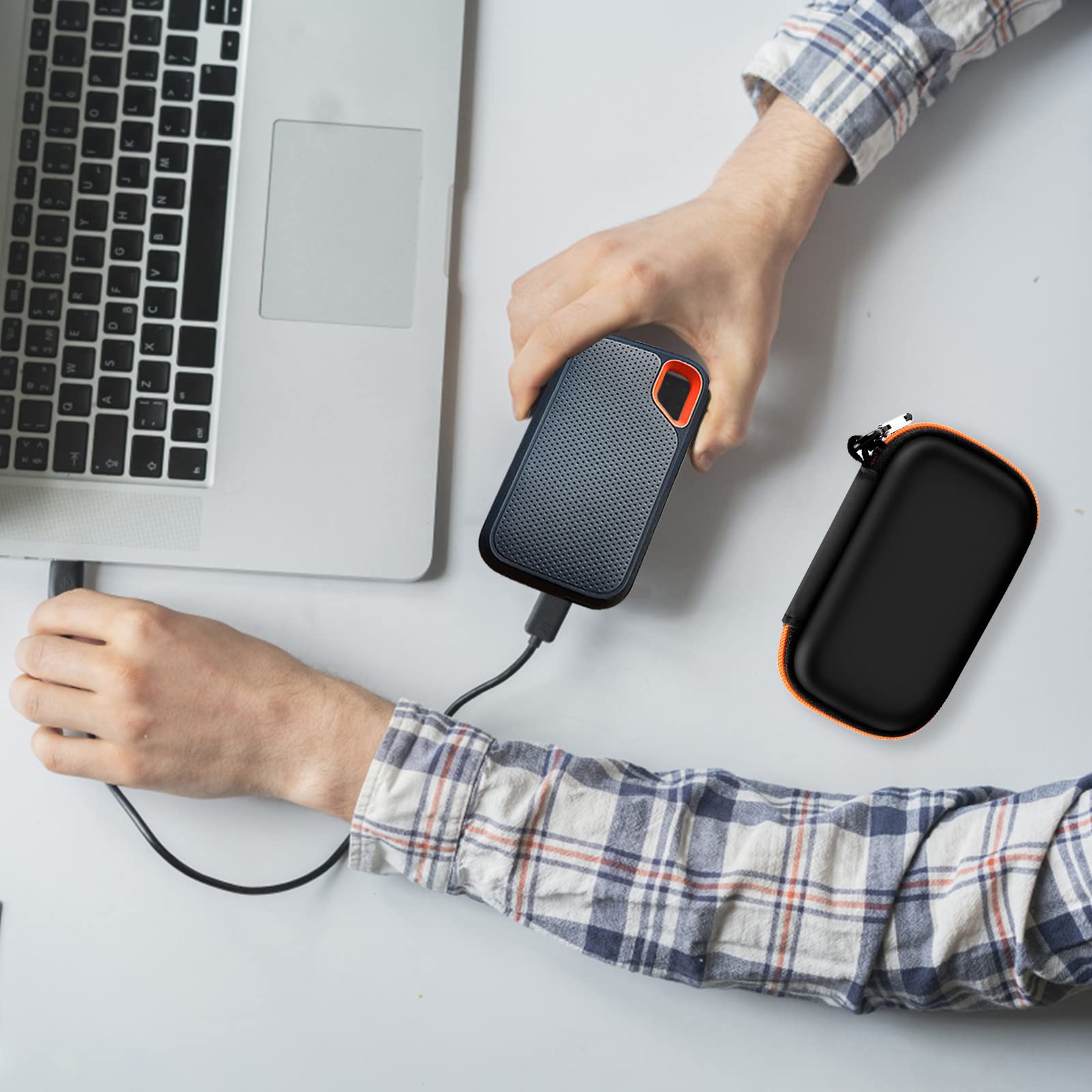 Black and orange SSD organizer beside a SanDisk drive connected to a laptop