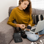 Black portable SSD case organizing an external drive and cable beside a laptop