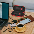 Black and red USB flash drive and SD card storage case open on a desk with electronics accessories