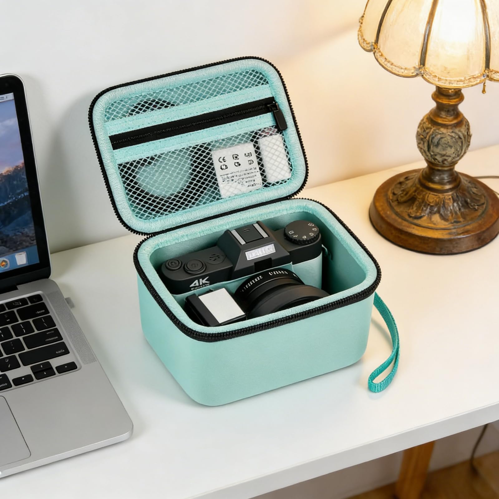 Open mint green camera case organizing a camera and accessories beside a laptop