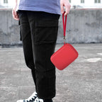 Red retro handheld console carrying case carried by the wrist strap outdoors