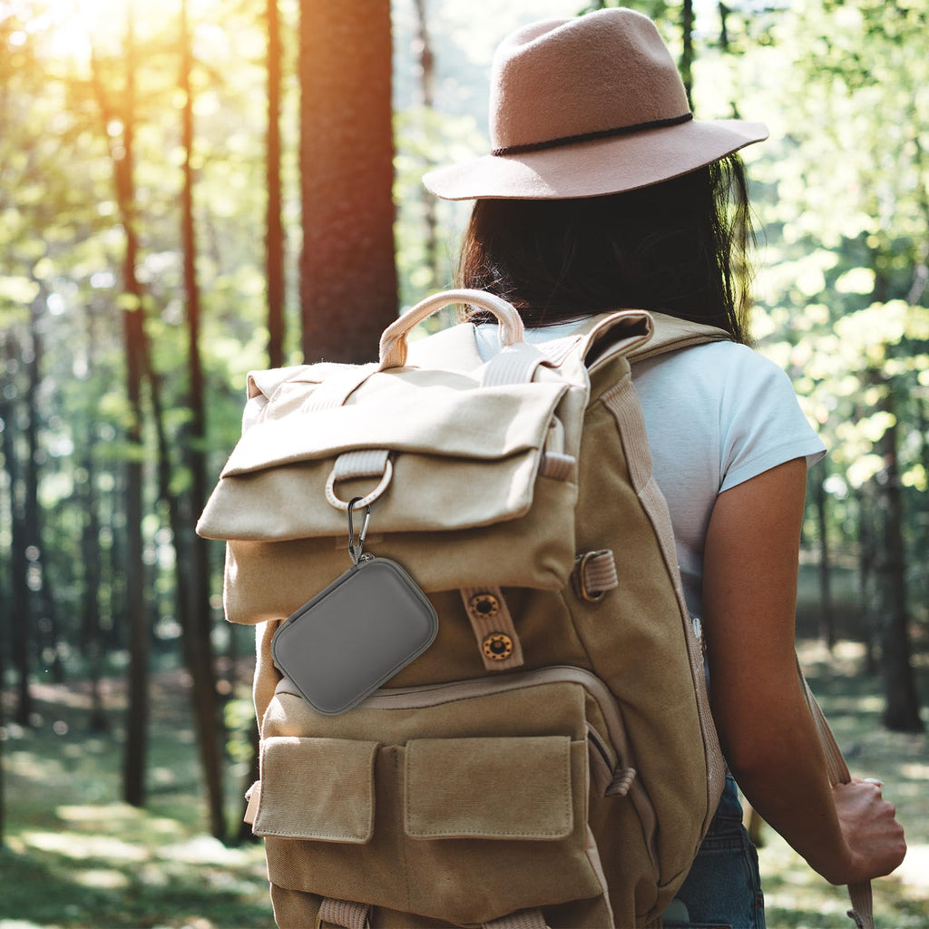Gray portable SSD case clipped to a hiking backpack