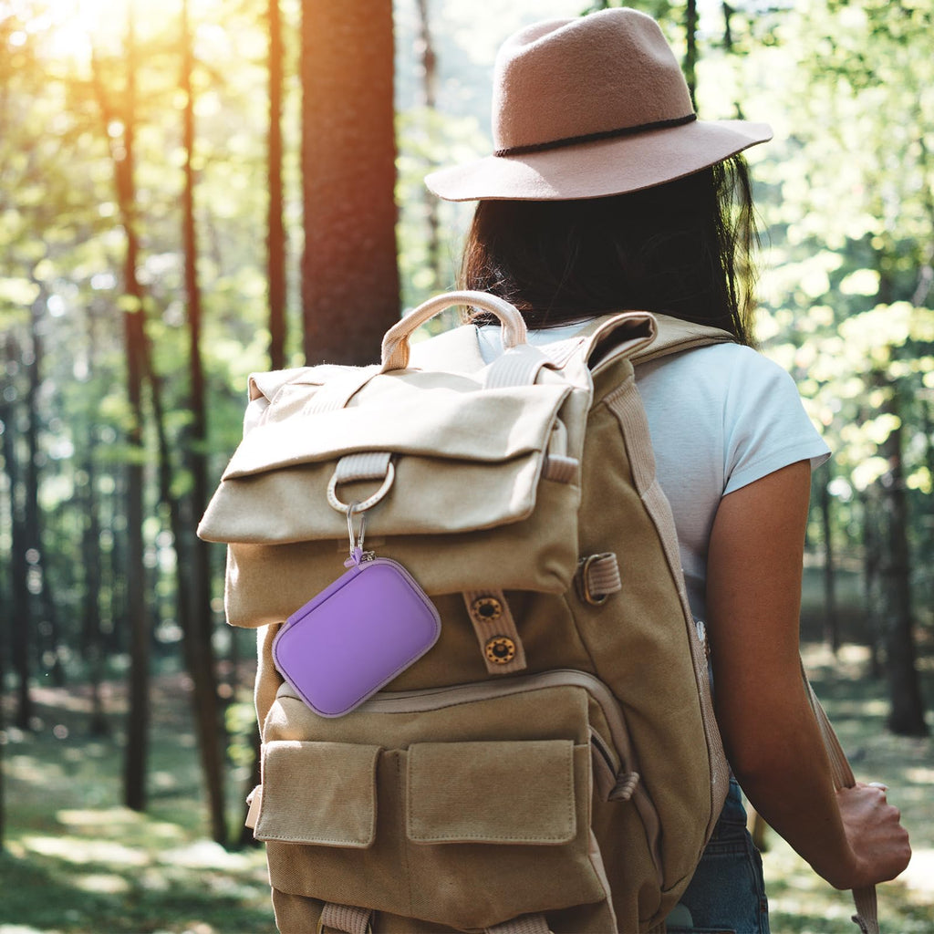 Purple portable SSD case clipped to a hiking backpack