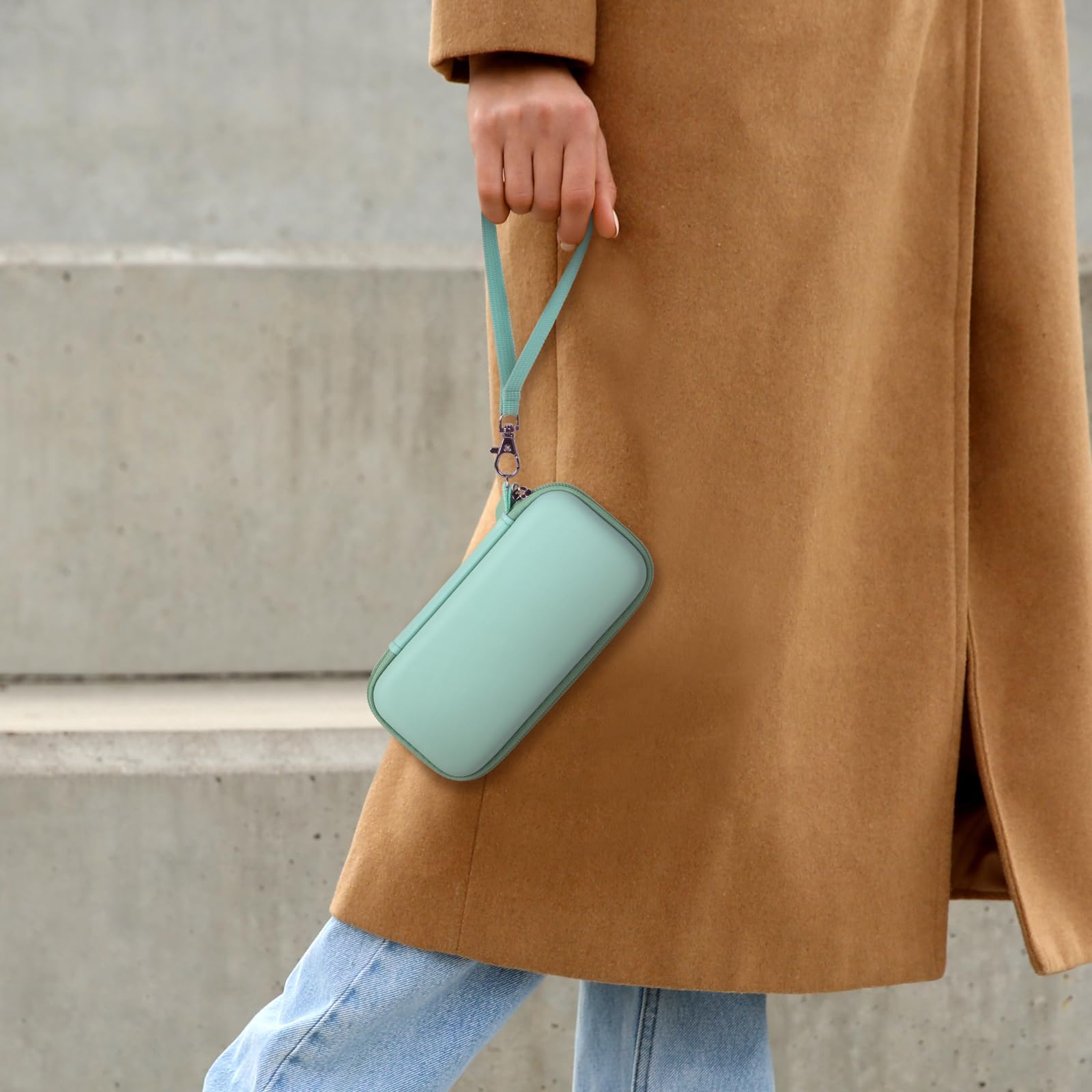 Person carrying the mint green power bank case by its wrist strap