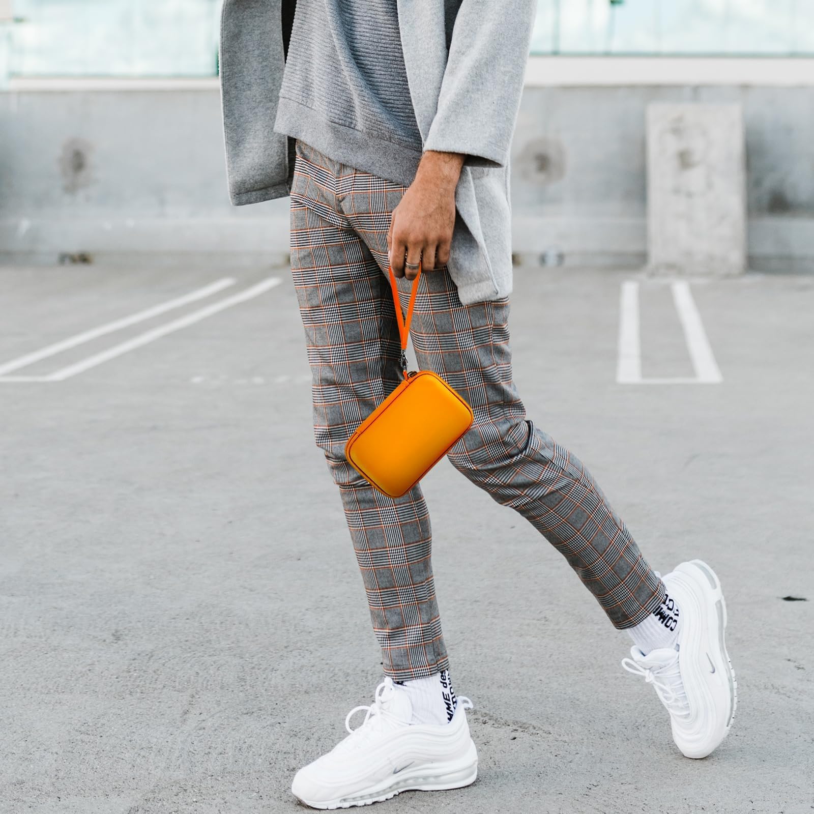 Person carrying the orange charging station case by its wrist strap