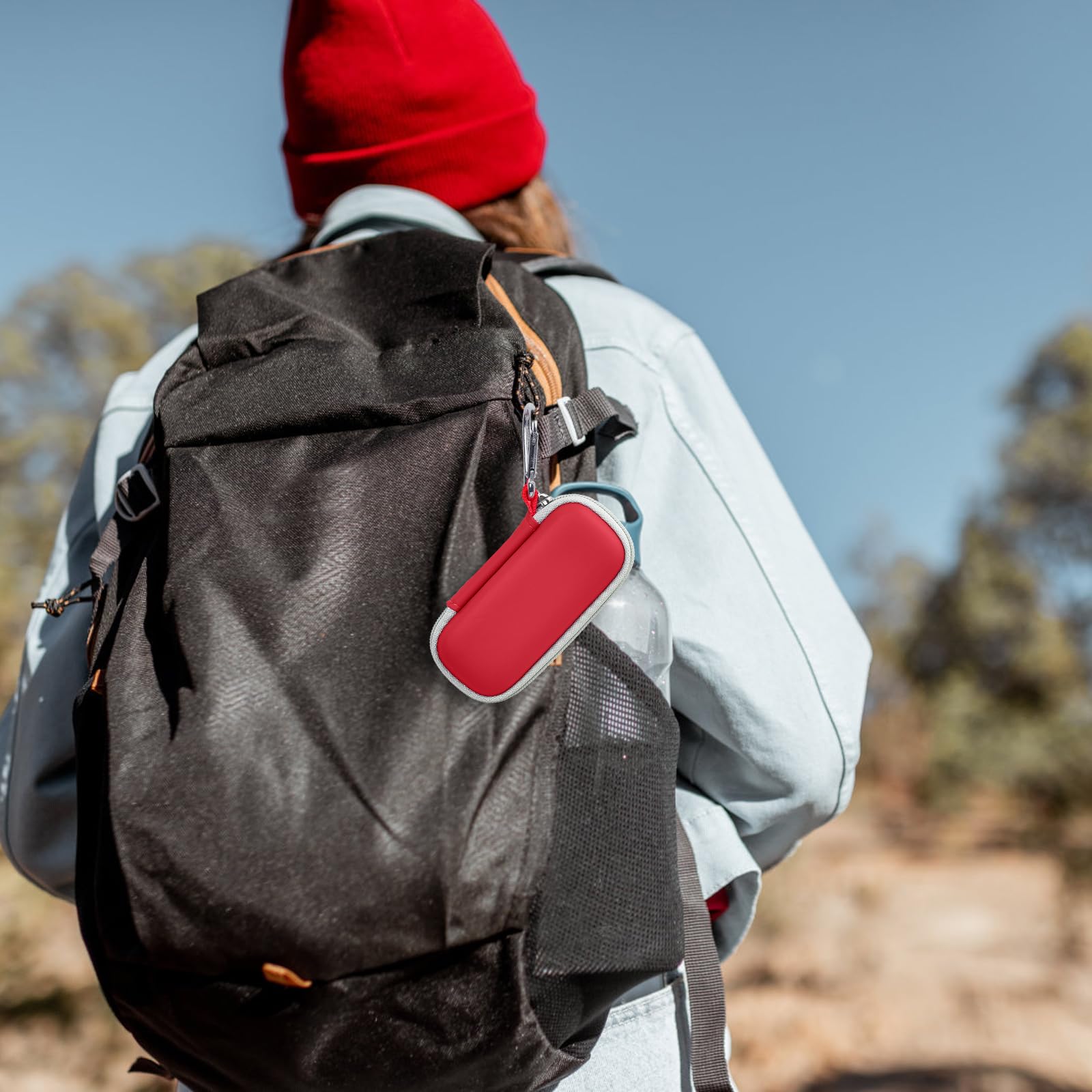 Red KardiaMobile case clipped to a hiking backpack