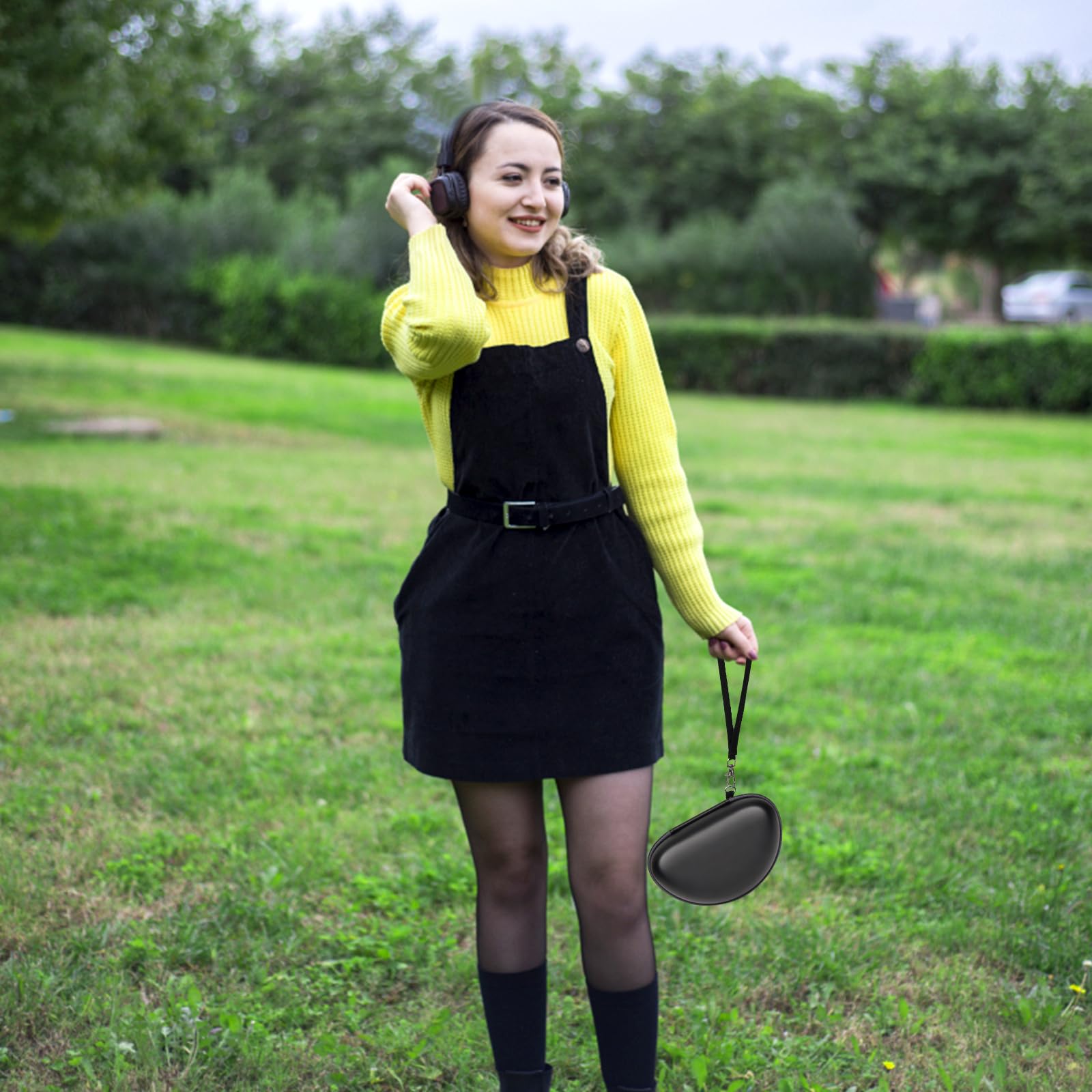Woman carrying the black headphone case by its wrist strap