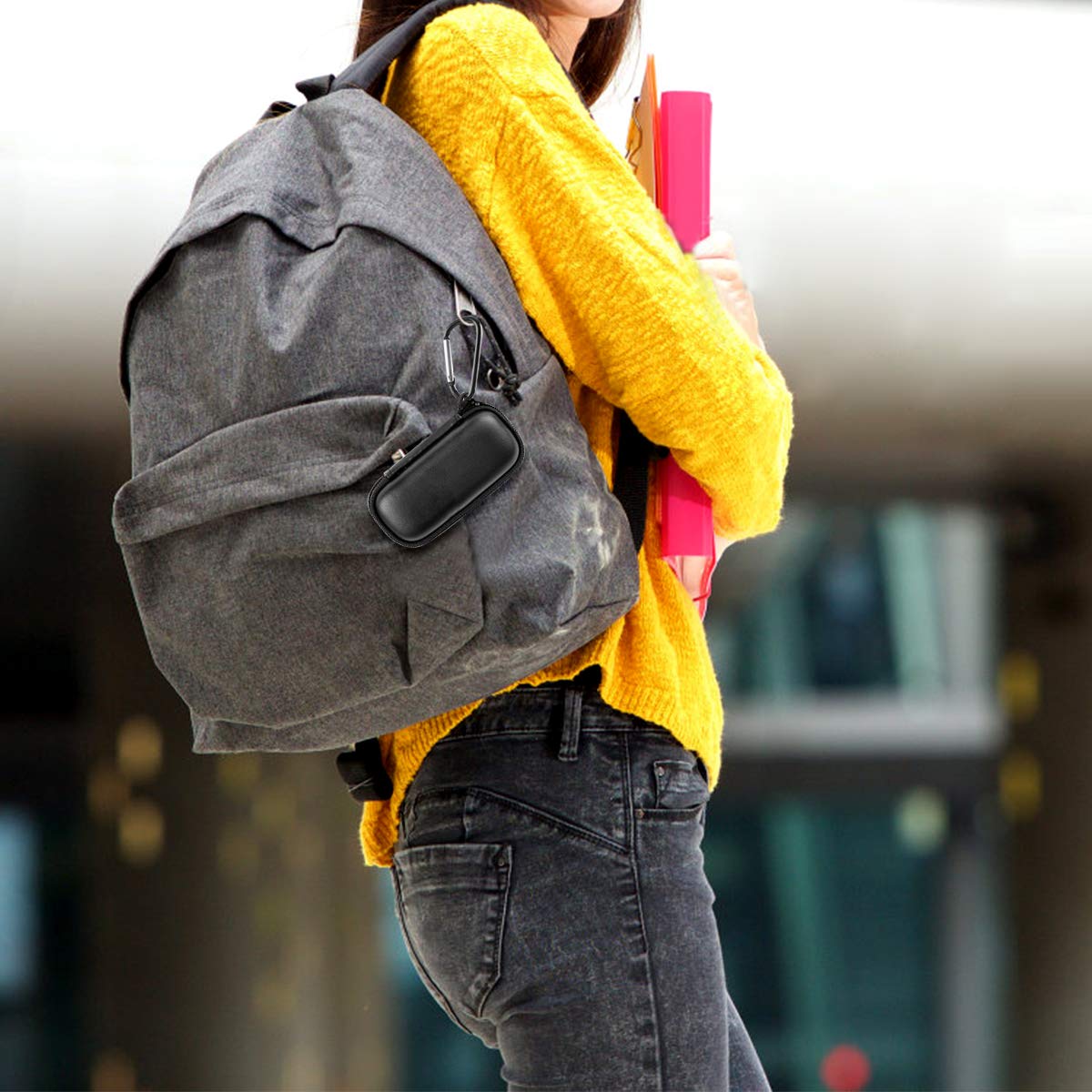 Black USB flash drive and SD card storage case clipped to a backpack
