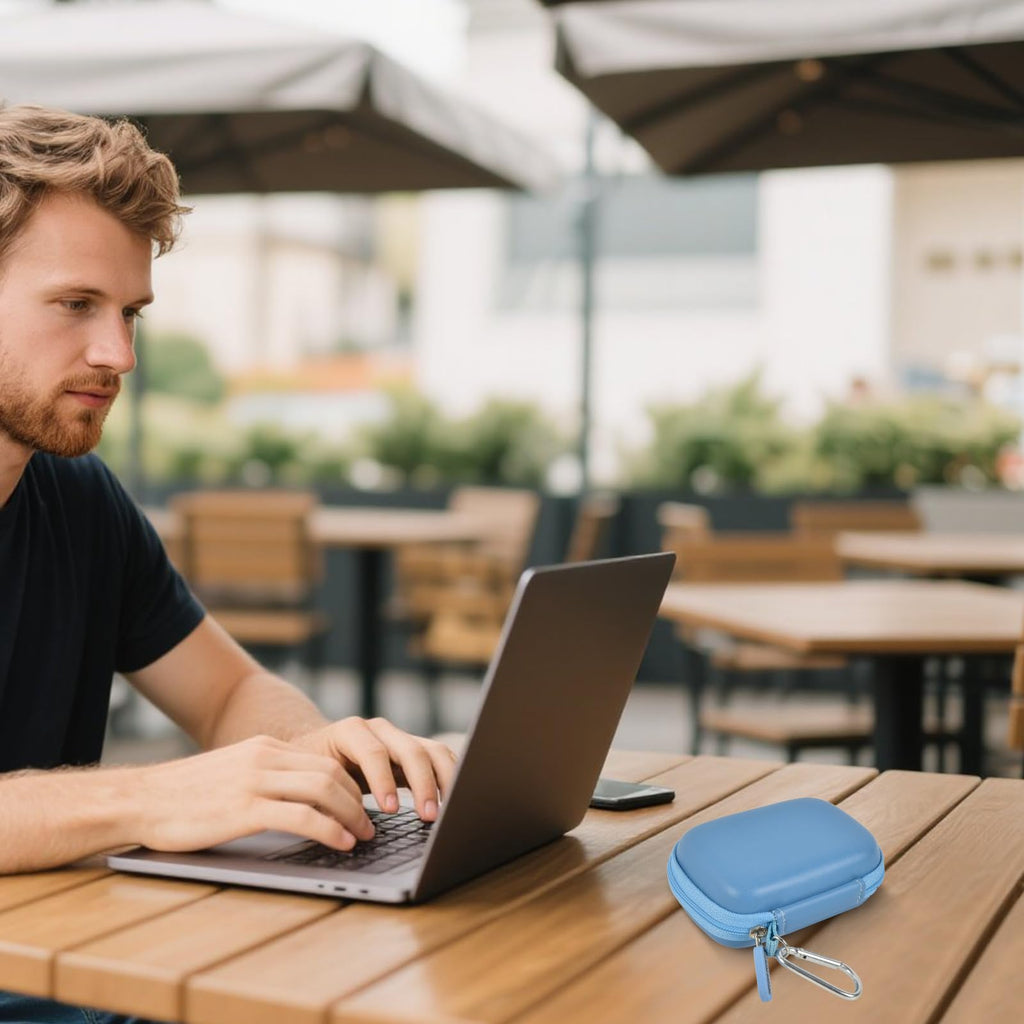 Blue portable SSD case beside a laptop at an outdoor cafe