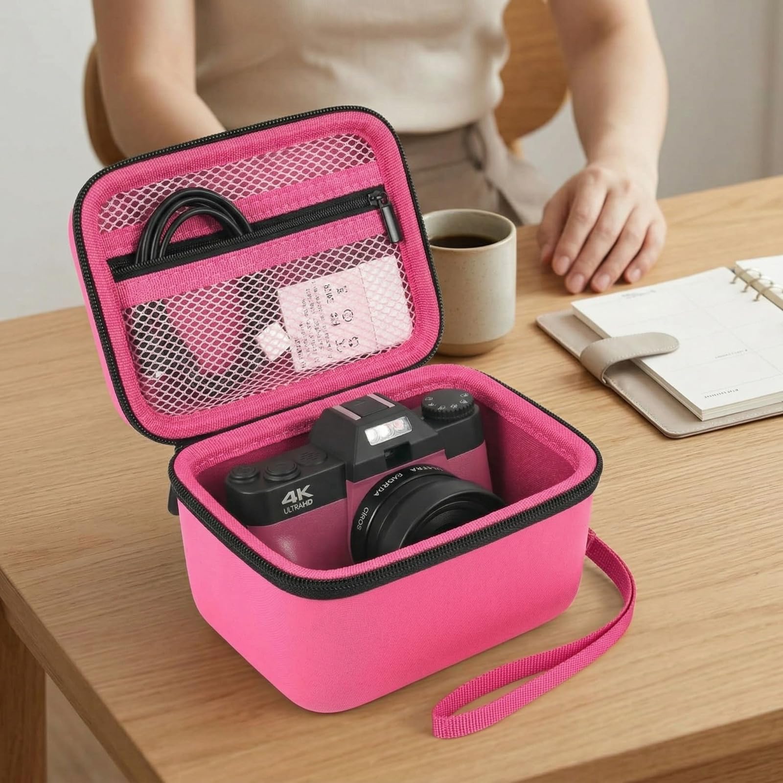 Open hot pink camera case organizing a camera and accessories on a desk
