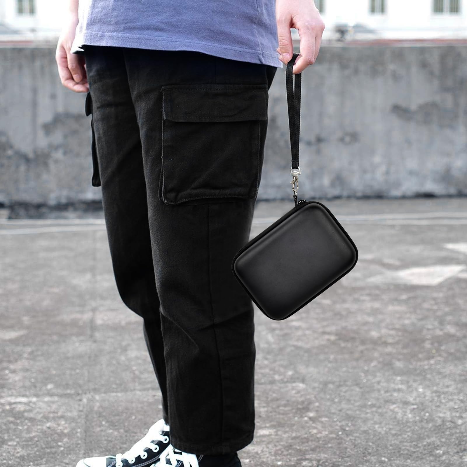 Black retro handheld console carrying case carried by the wrist strap outdoors