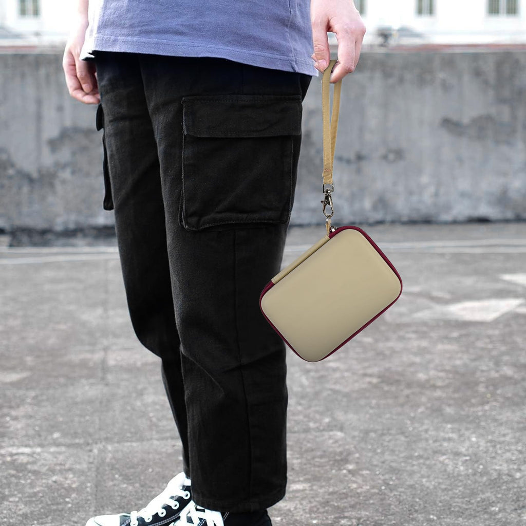 Beige with burgundy trim retro handheld console carrying case carried by the wrist strap outdoors